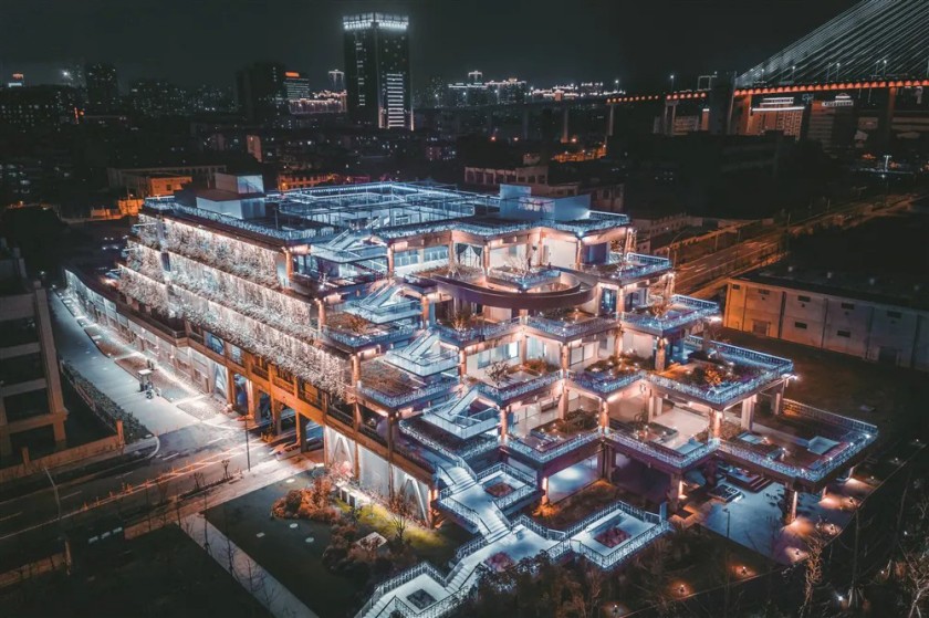 The illuminated Green Hill Shanghai at night, highlighting its layered design and integration with the city's vibrant skyline.